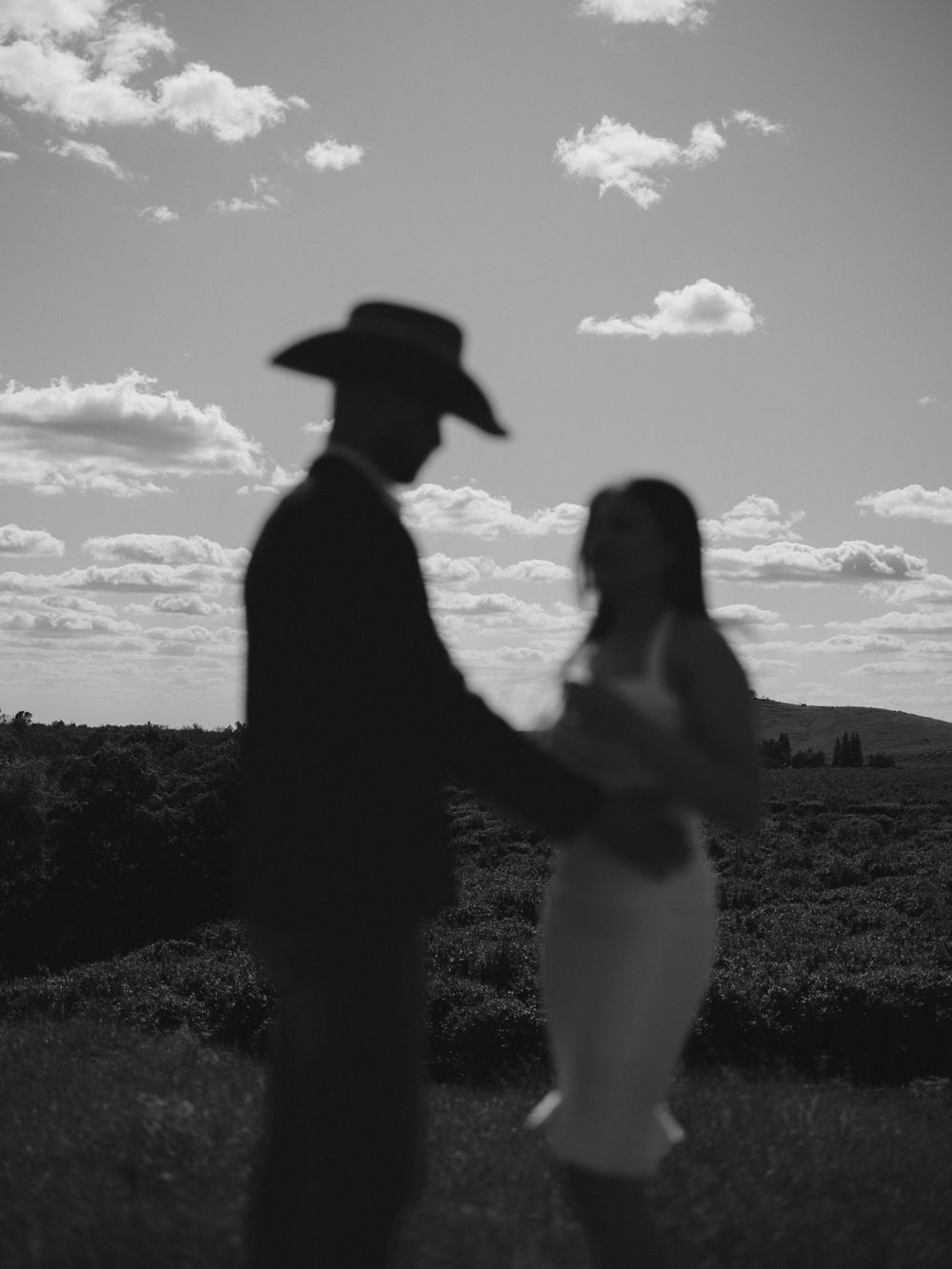 Silhouetted figures create dramatic composition against bright cloudy sky.