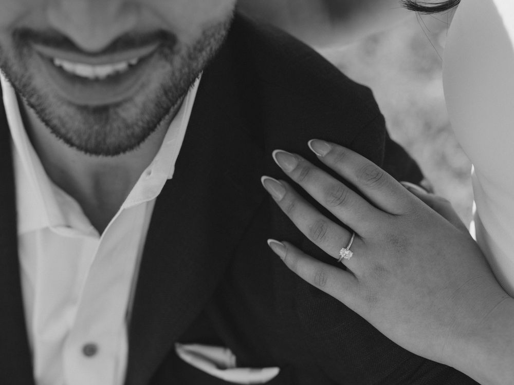 Close-up shot showing hand with engagement ring resting on formal attire.
