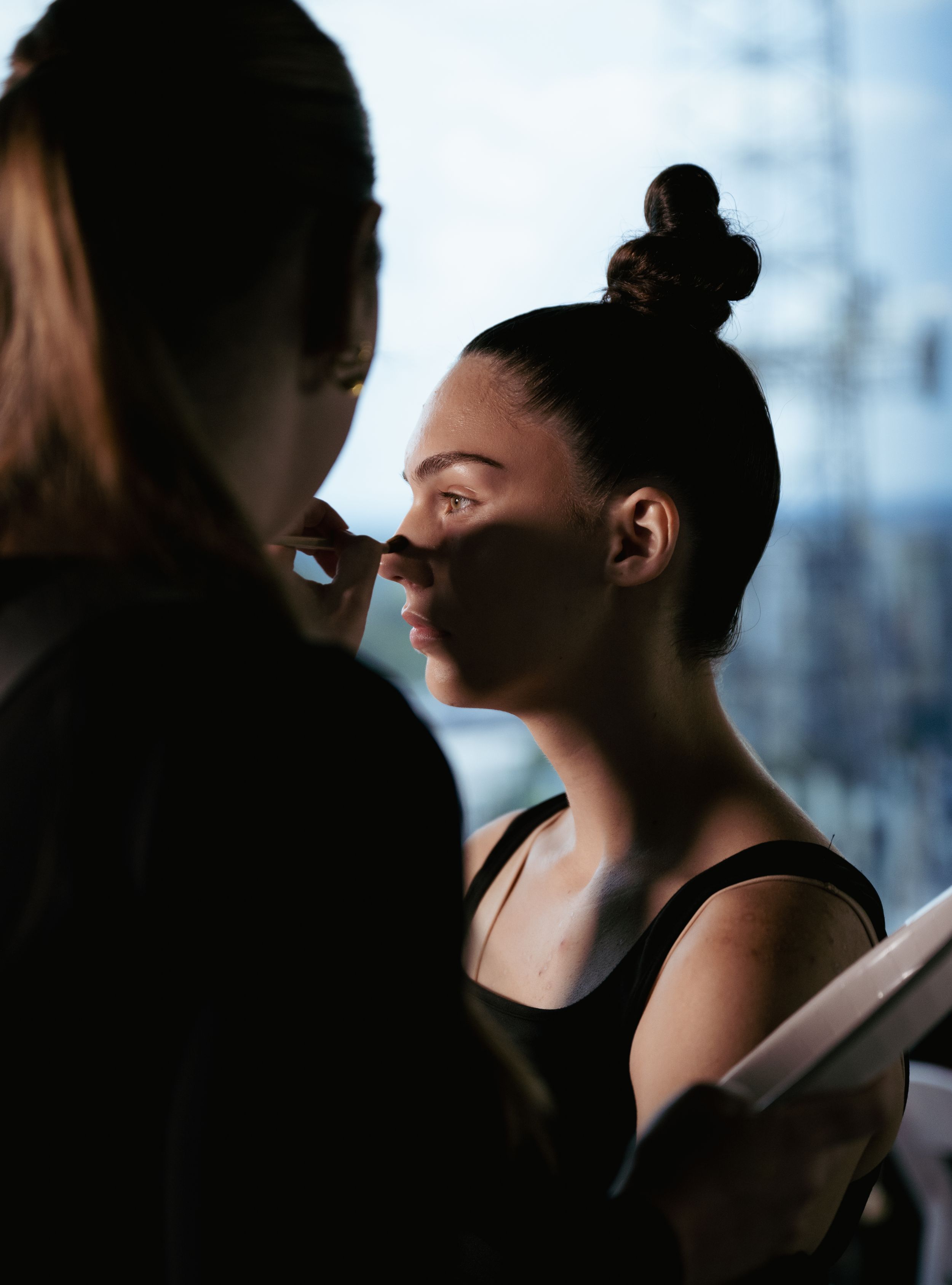 Behind-the-scenes makeup application in dramatic lighting.