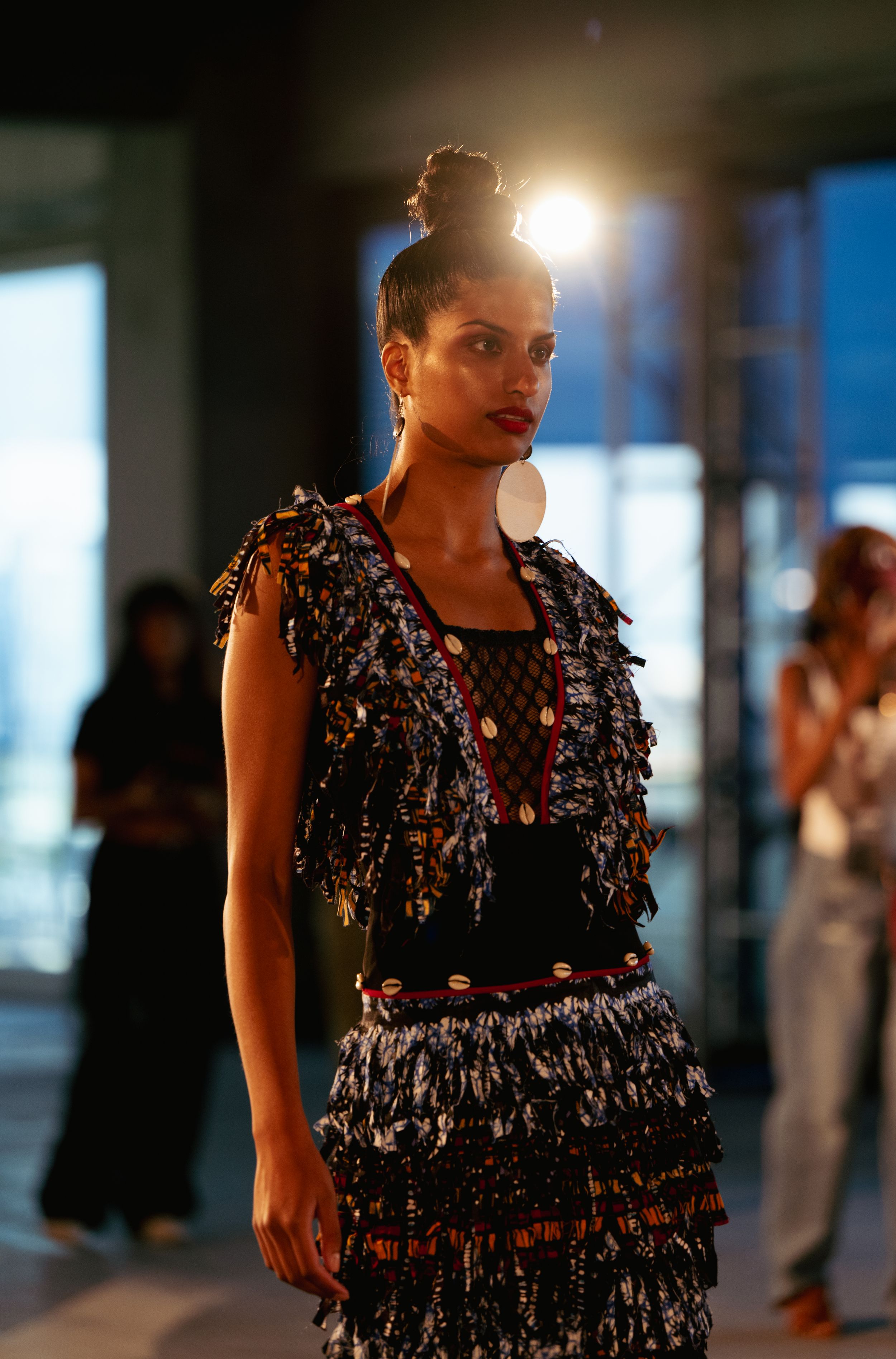 Dramatic fashion shot of model in textured black evening wear with backlit glow.