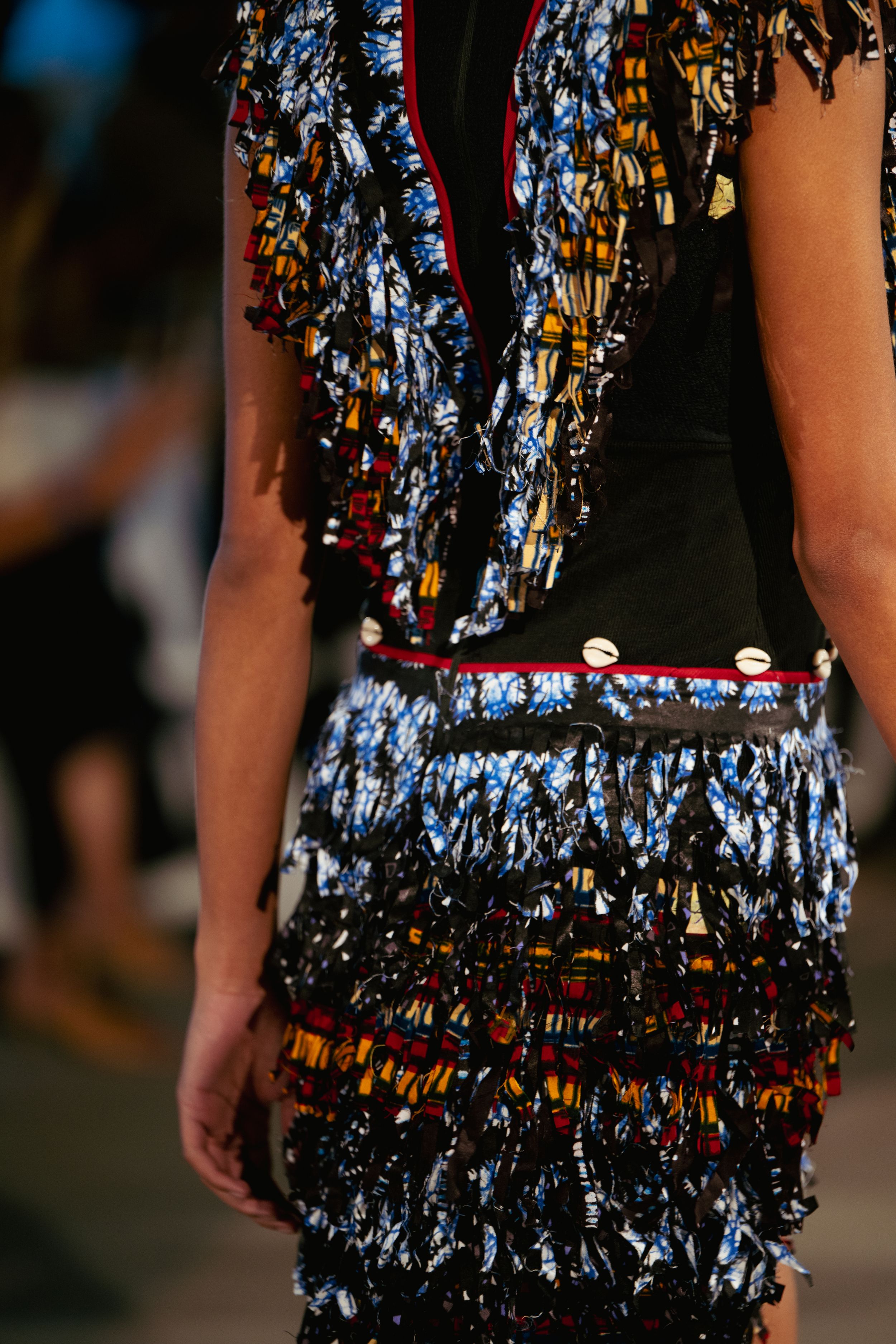 Detail shot of textured metallic fringe dress on fashion runway.