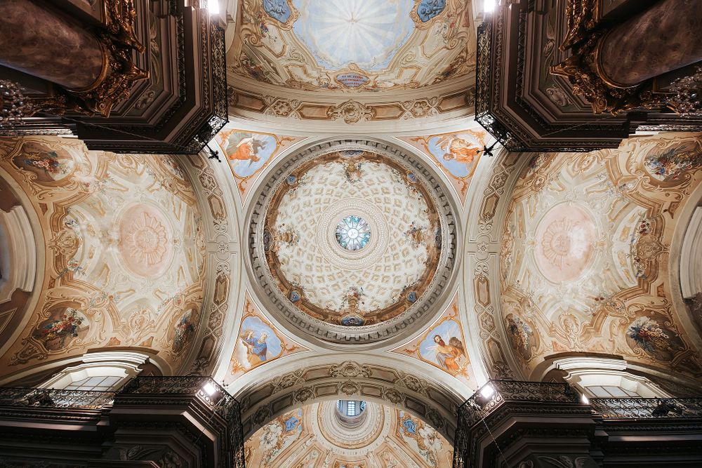 Stunning ornate baroque church ceiling with painted dome, frescoes, and gilded architectural details.