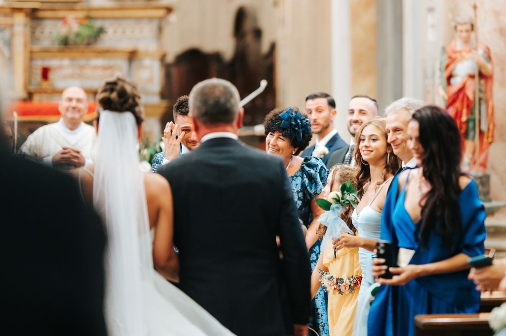 Bride at altar greeted by emotional family and bridesmaids in blue dresses during ceremony.