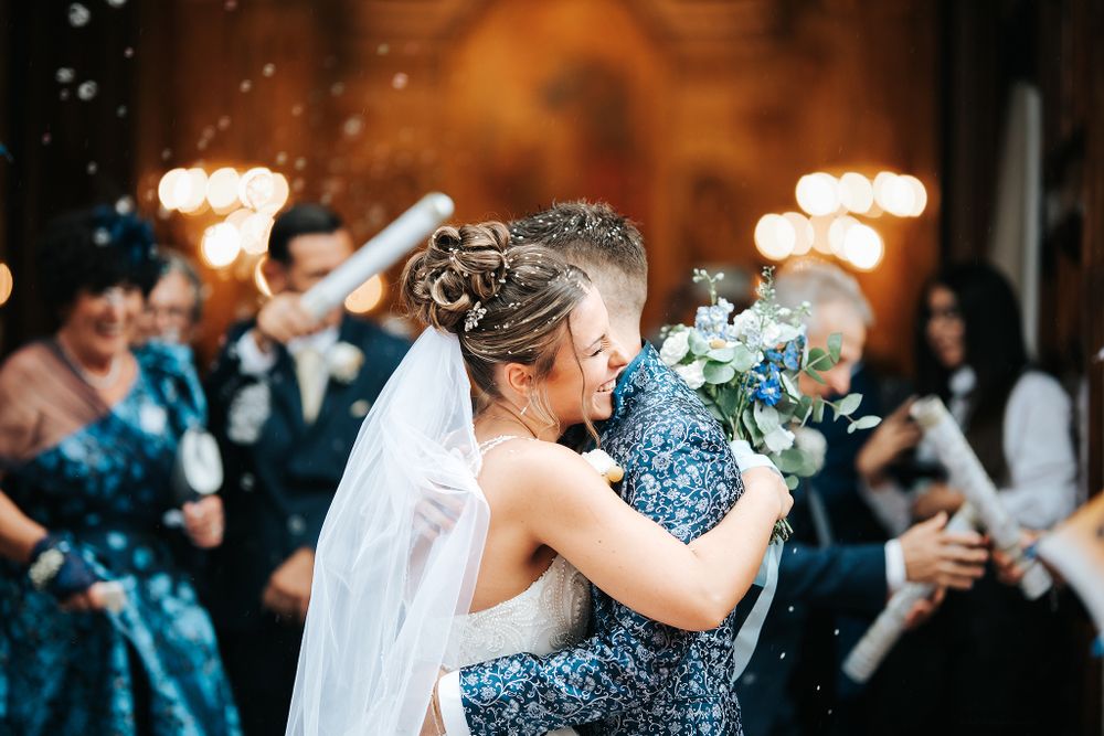 Bride embraces guest warmly as confetti fills the air during joyful wedding celebration.