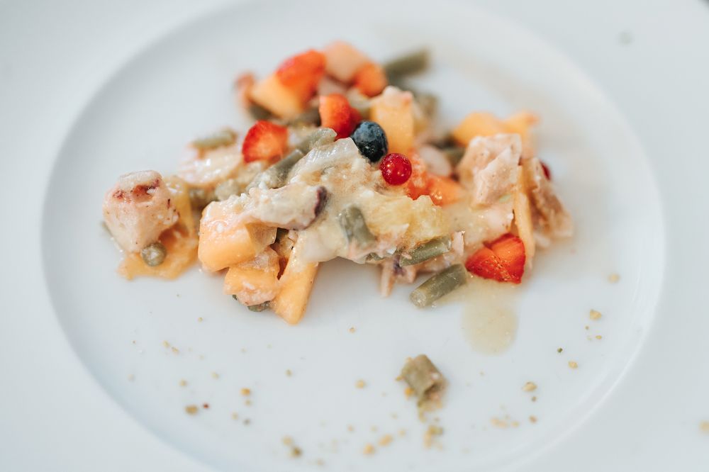 Elegant wedding reception dish featuring pasta with fresh strawberries, green beans, and cream sauce.
