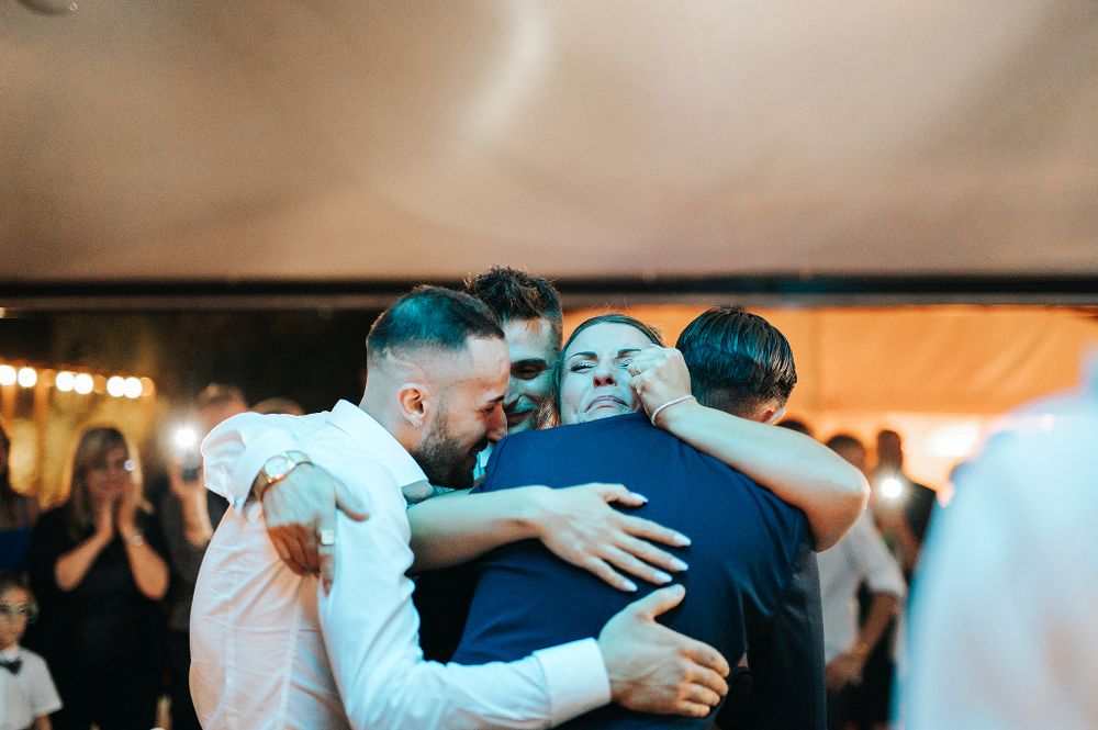 Bride and two guests sharing a warm group hug on the wedding reception dance floor.