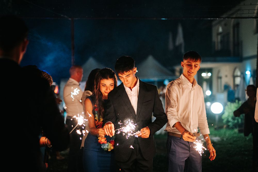 Young guests holding sparklers at an outdoor evening wedding reception celebration.