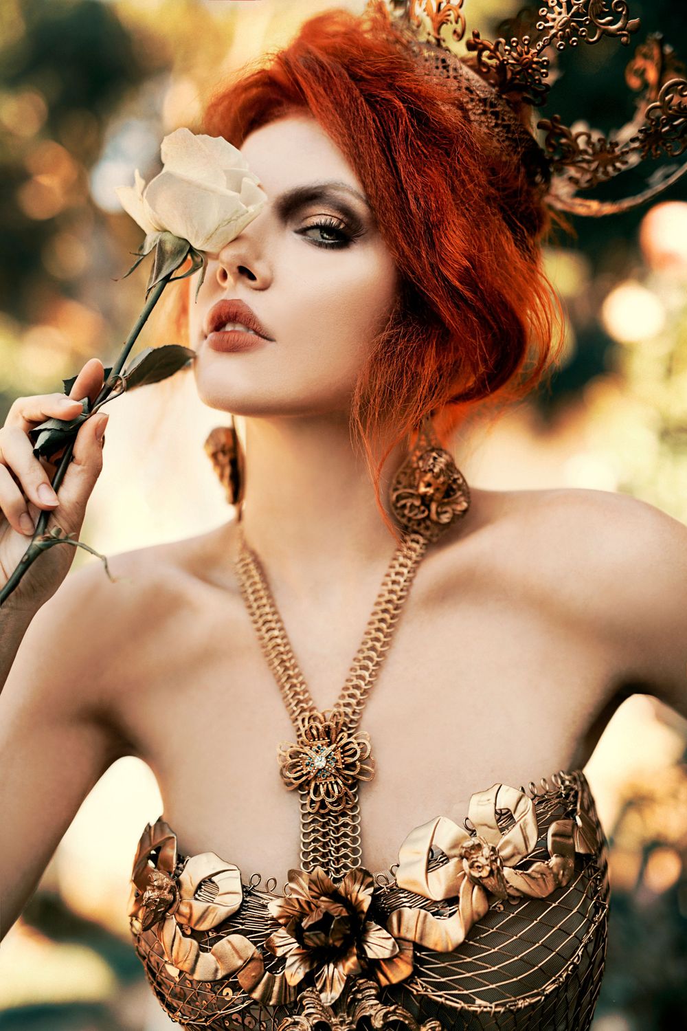 Fine art portrait of a red haired woman holding a white rose, wearing gold jewellery