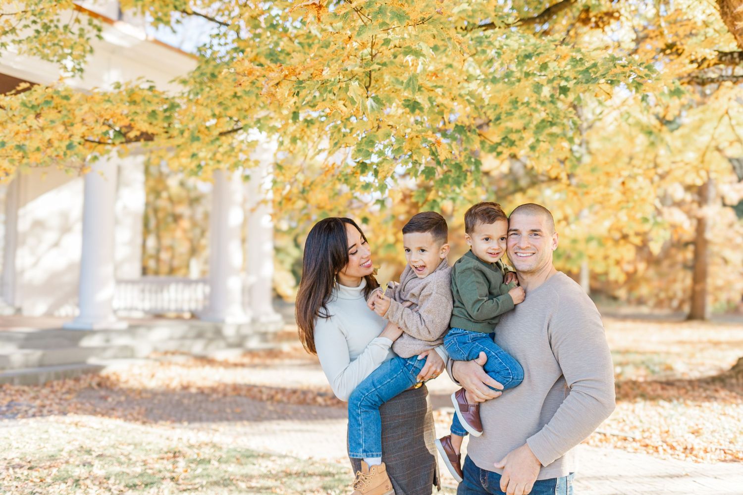 Family smiling with fall leave behind them during a fall family session in the Hudson Valley of NY