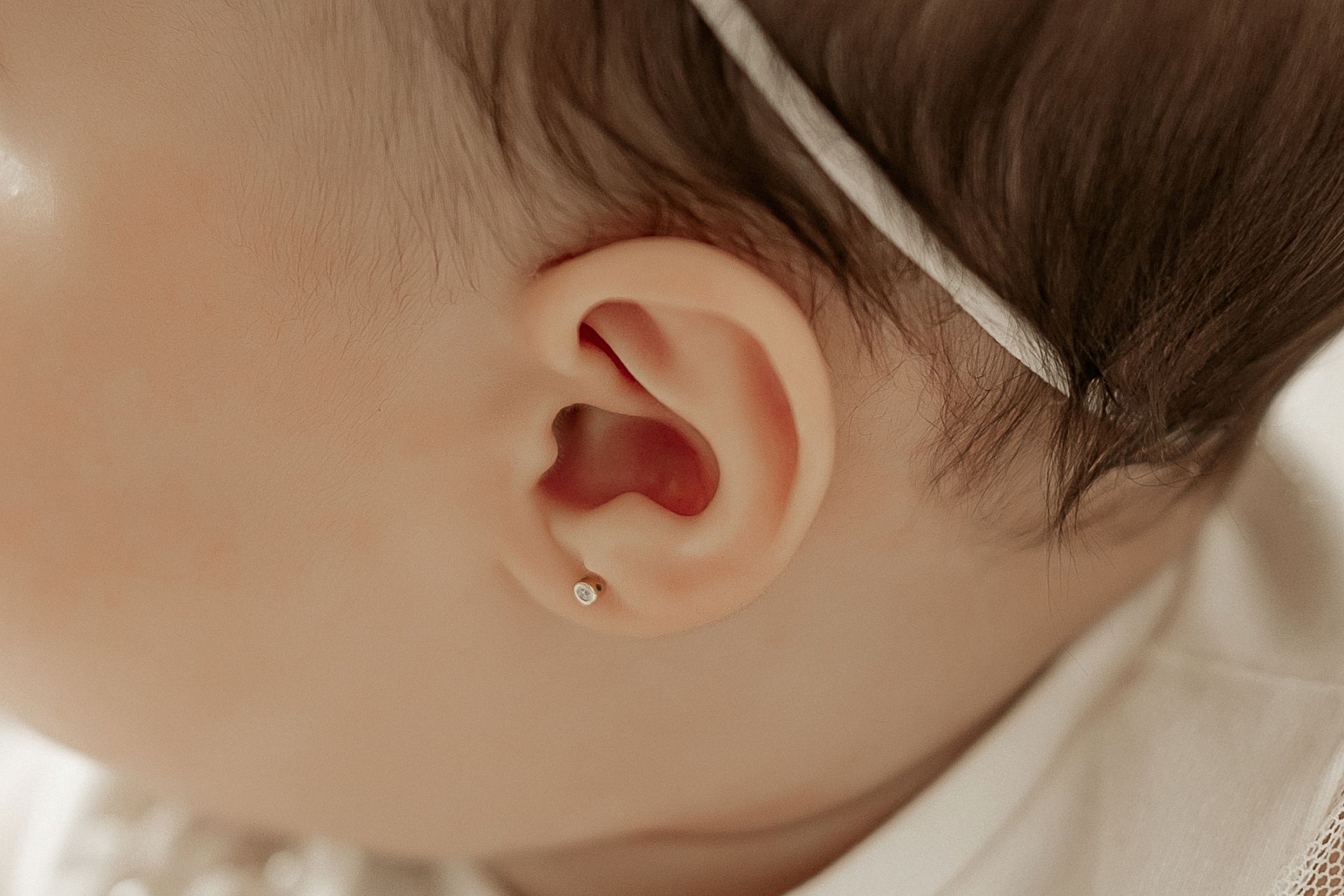 Close-up macro photograph of a baby's ear against a soft white background.