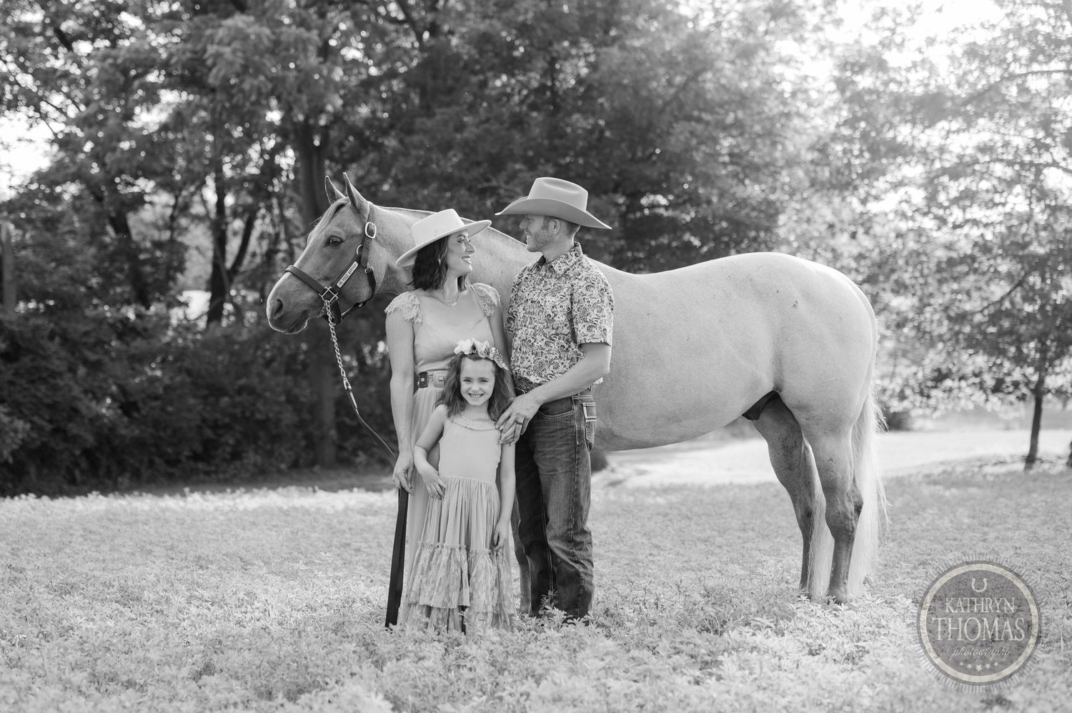 A black and white portrait of a family with their horse in a pastoral setting.