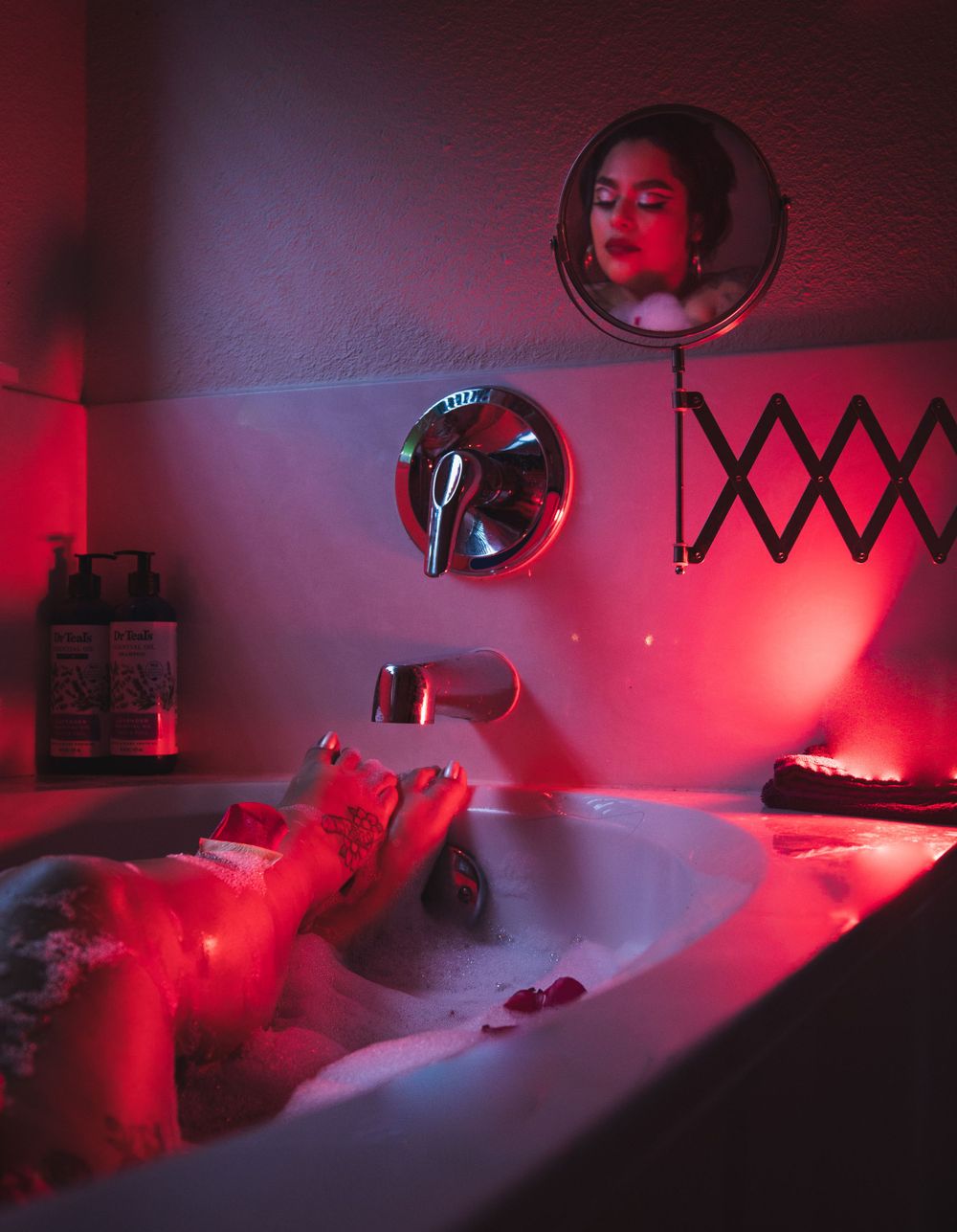 A boudoir bathtub scene illuminated by red lighting with mirrors and expandable fixtures on the wall.