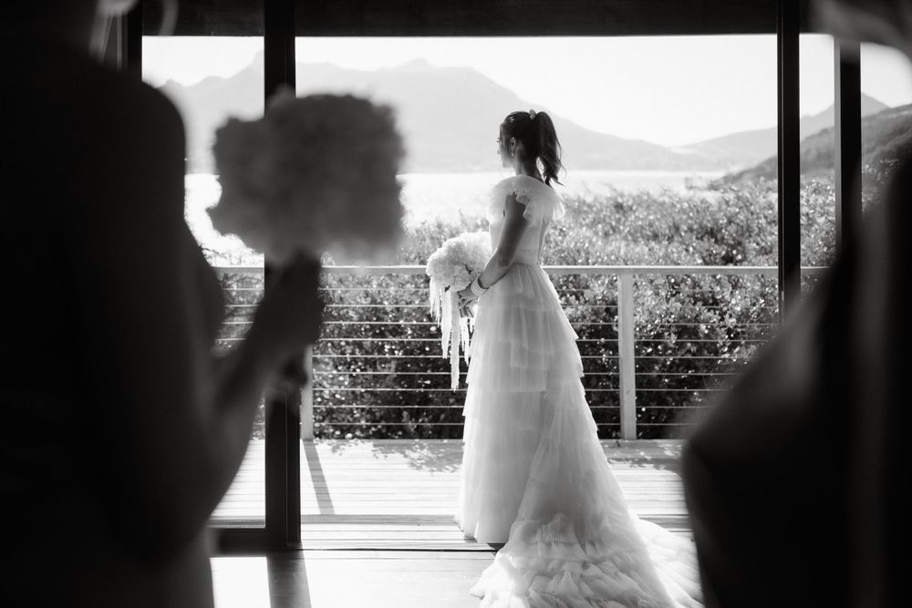 Silhouetted wedding dress figure against bright window with mountain landscape view.