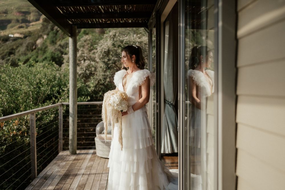 Wedding dress silhouette against glass doors on outdoor porch with mountain view.