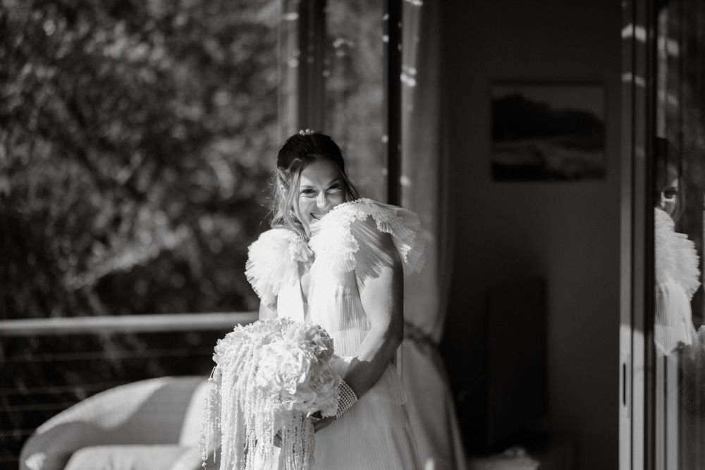 Black and white portrait of bride holding bouquet in sunlit room.
