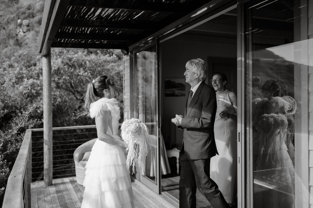 Black and white candid moment captured on wedding venue porch.