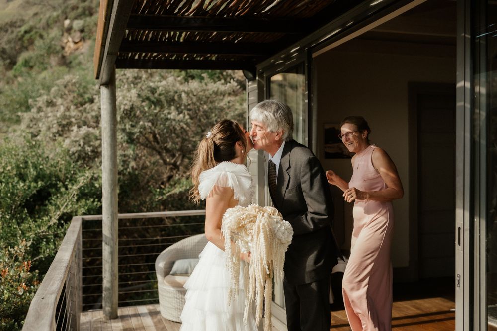 Intimate moment captured under rustic wooden pergola at outdoor wedding.