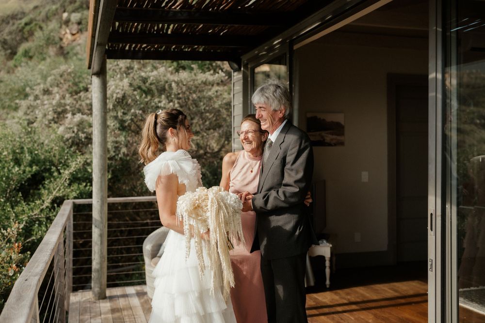 A touching family moment on a sunlit porch during a wedding celebration.