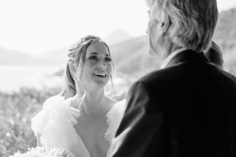 A black and white wedding moment captured outdoors with scenic mountain views in the background.