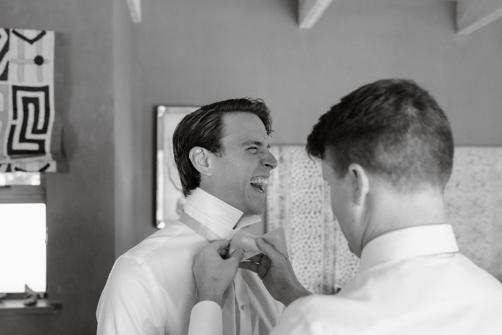 Black and white photo of someone adjusting a bowtie before a formal event.