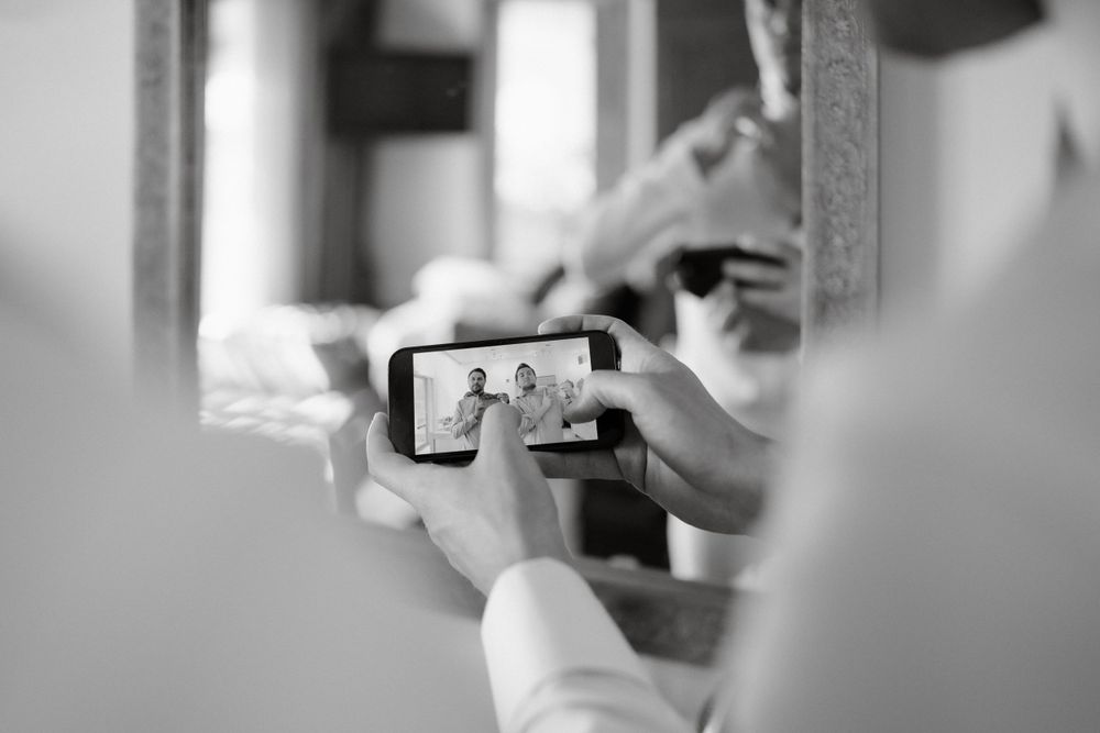 A candid black and white photo of someone taking a selfie in a mirror.