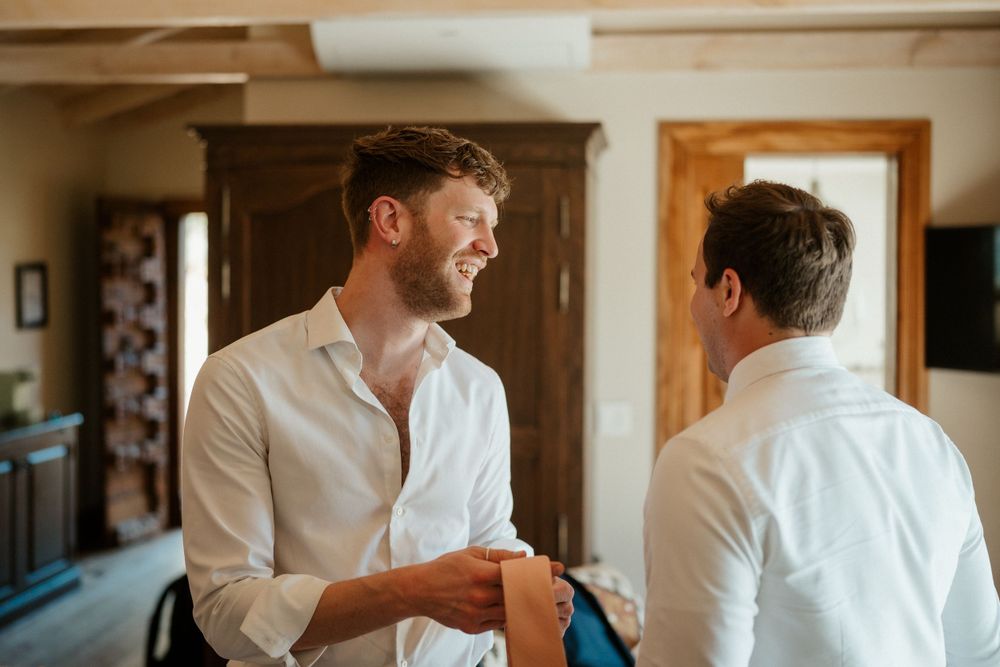 Two people in white dress shirts having an animated conversation while standing in a bright interior room.