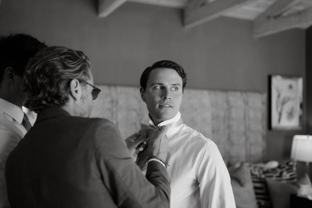 A black and white photograph shows two men in business attire having a conversation in an interior setting.