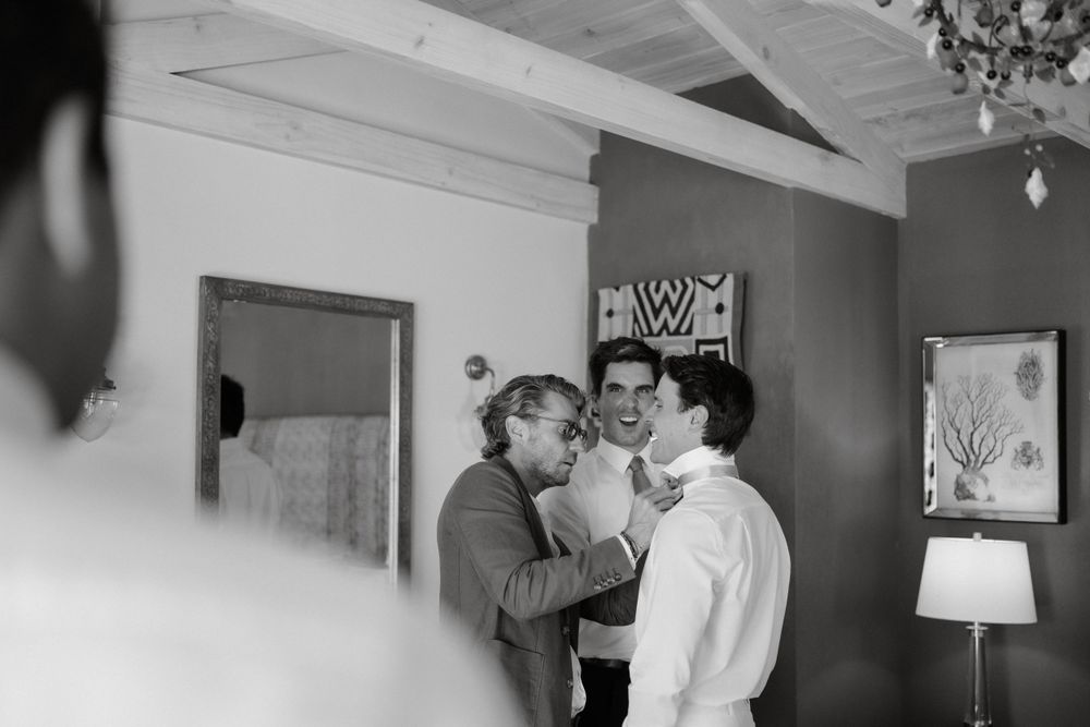 Three people share an intimate candid moment together in front of a wall with artwork and lamp.