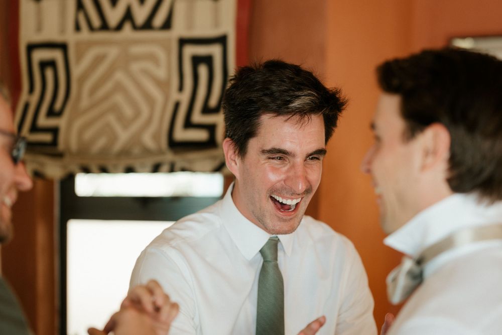Two people sharing a joyful moment in formal attire with a patterned wall decoration in the background.