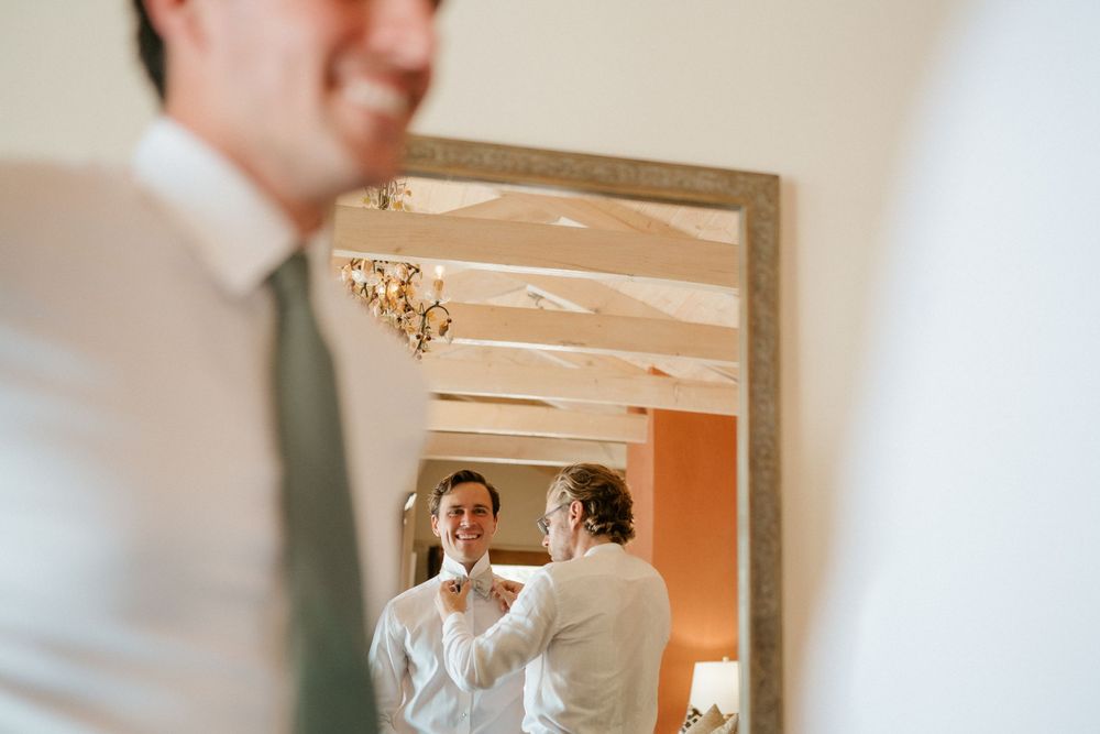 Reflection in wooden framed mirror showing preparation activities with warm lighting.