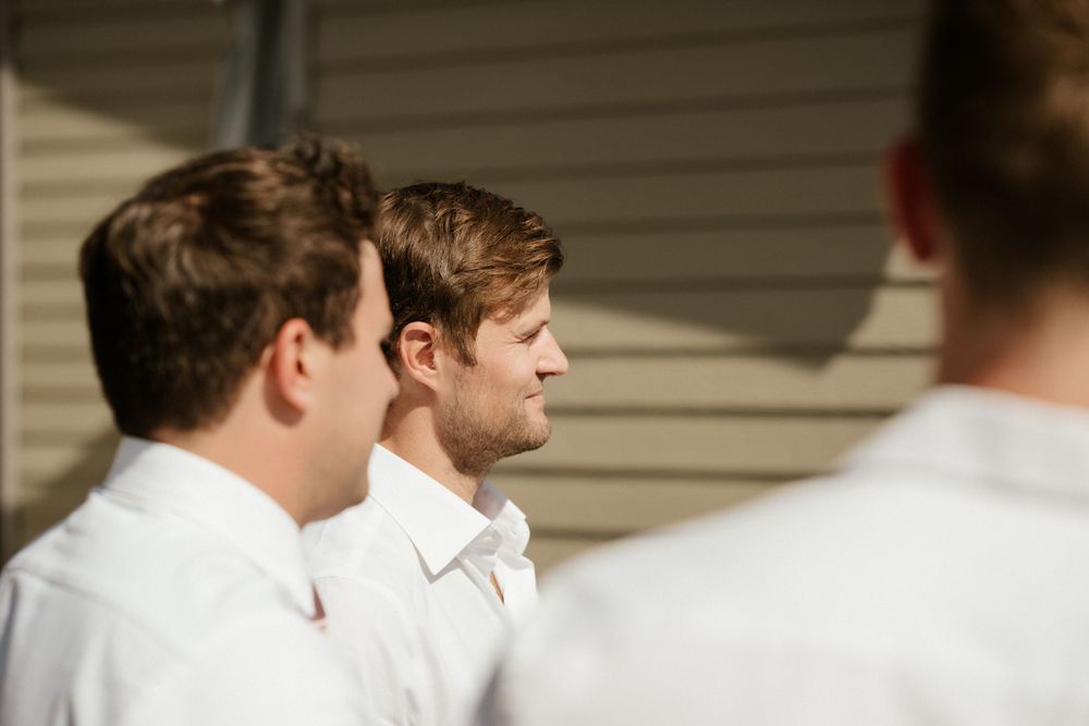 Groomsmen in white shirts stand together before a wedding ceremony.