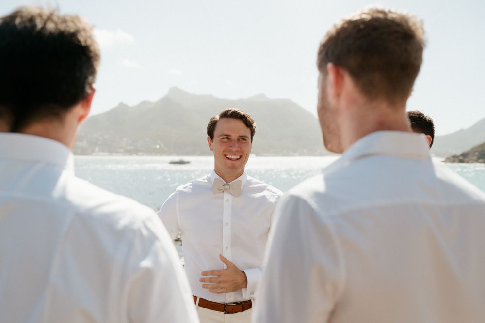 Wedding party members in white shirts gather near a scenic coastal overlook.