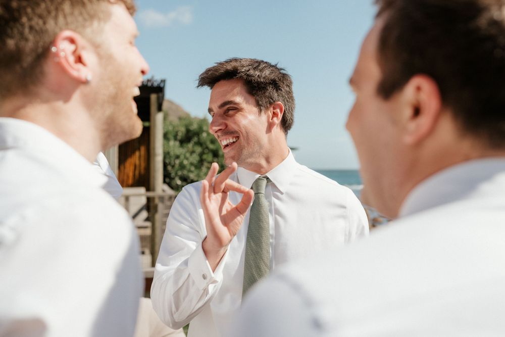 Groomsmen in white shirts share a cheerful moment during wedding preparations.