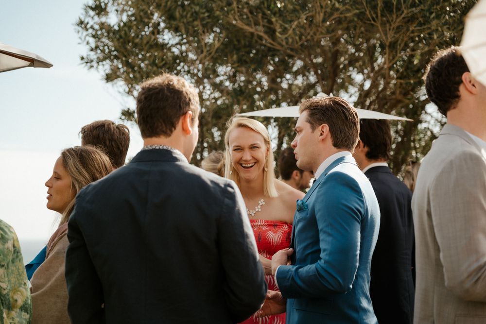 Wedding guests mingling during an outdoor cocktail hour under trees.