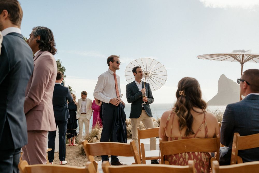 Outdoor wedding ceremony setup with white parasol and mountain backdrop.