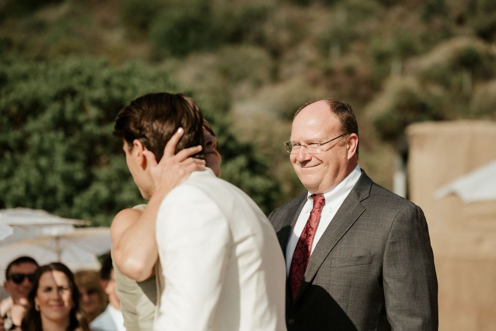 An emotional moment between two people during a wedding ceremony with mountains in the background.
