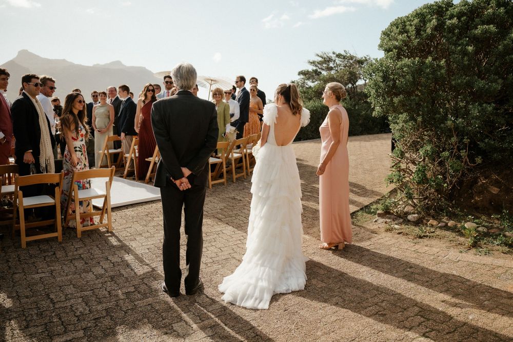 An outdoor wedding ceremony with mountain views and wooden chairs set up for guests.