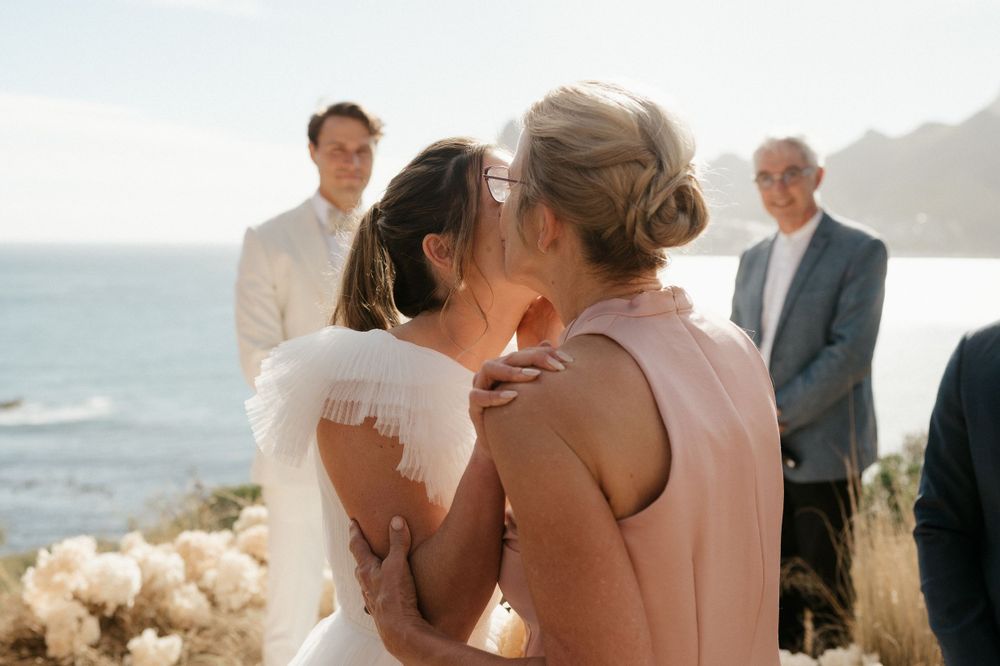 Intimate wedding ceremony taking place on scenic coastal cliff overlooking the ocean.