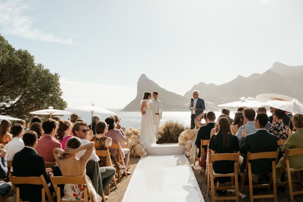 Outdoor wedding ceremony with mountain backdrop and white aisle runner.