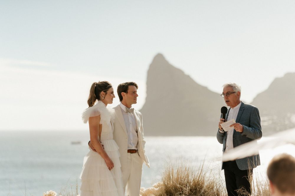 Wedding ceremony taking place on a clifftop overlooking dramatic coastal views.
