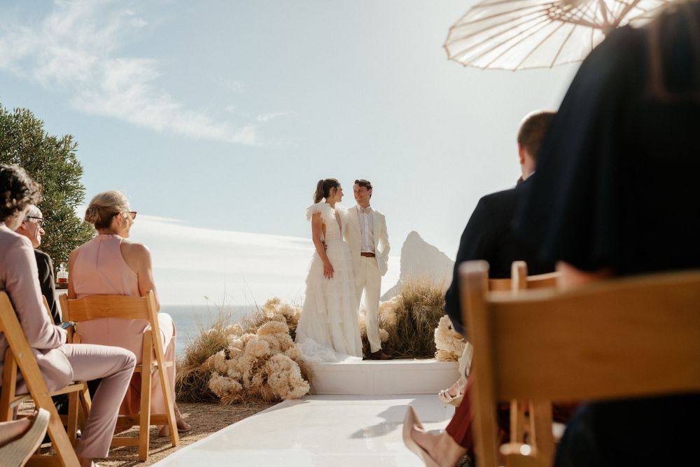An outdoor wedding ceremony with white parasols and mountain views.