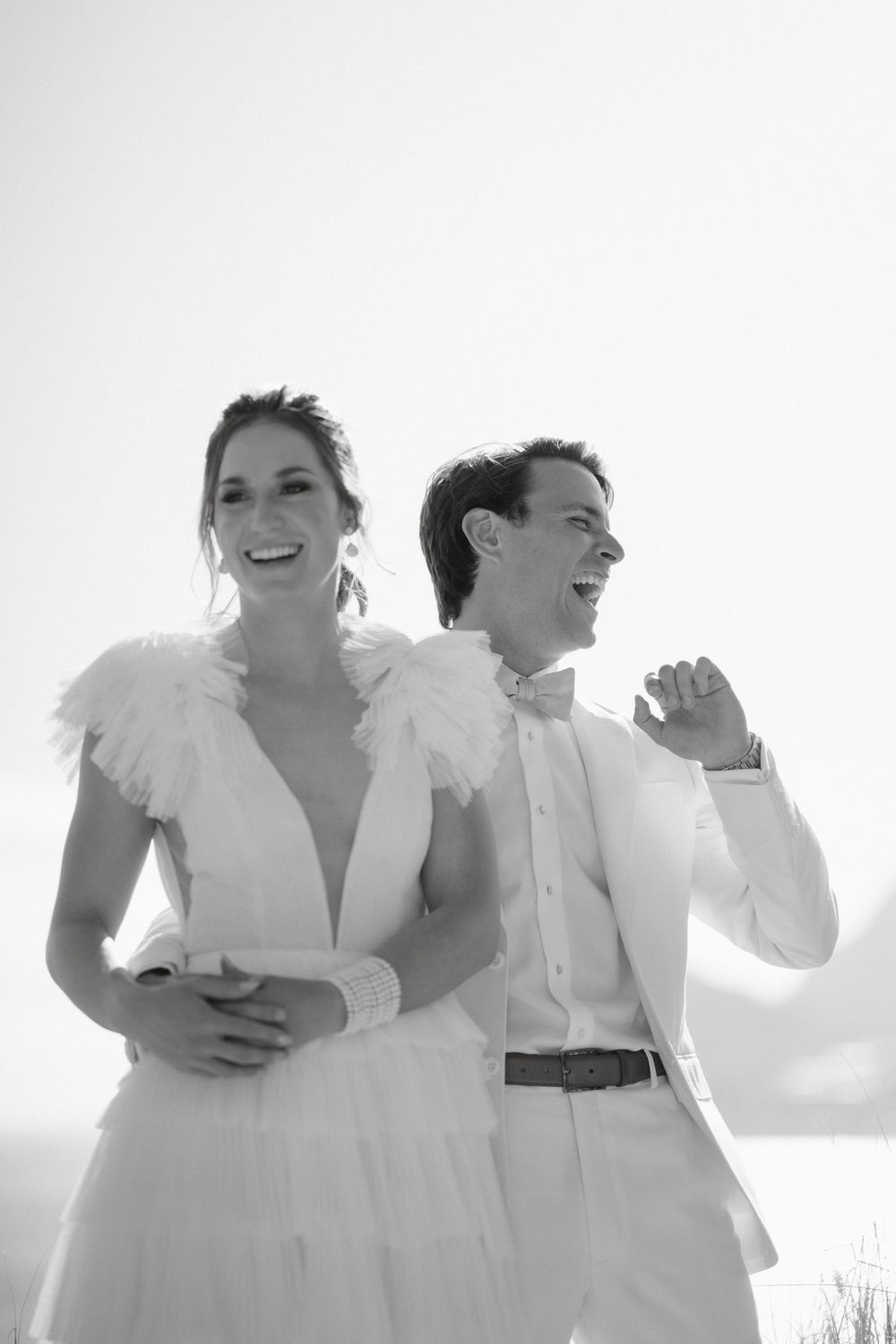 Black and white portrait of couple in wedding attire sharing a joyful moment.