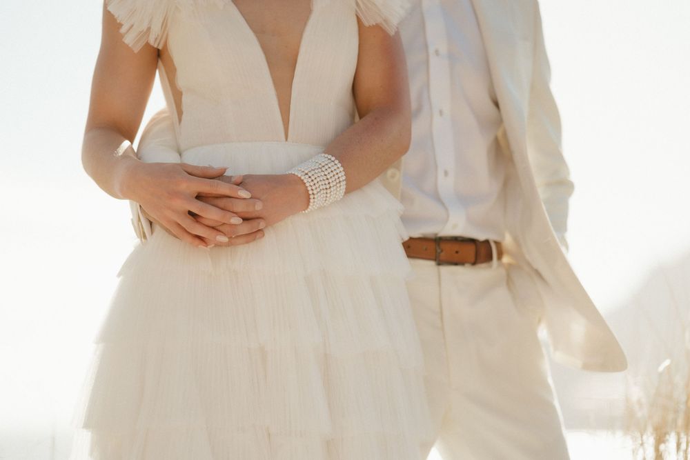 Close-up view of a bride's white lace wedding dress with delicate bracelet details.