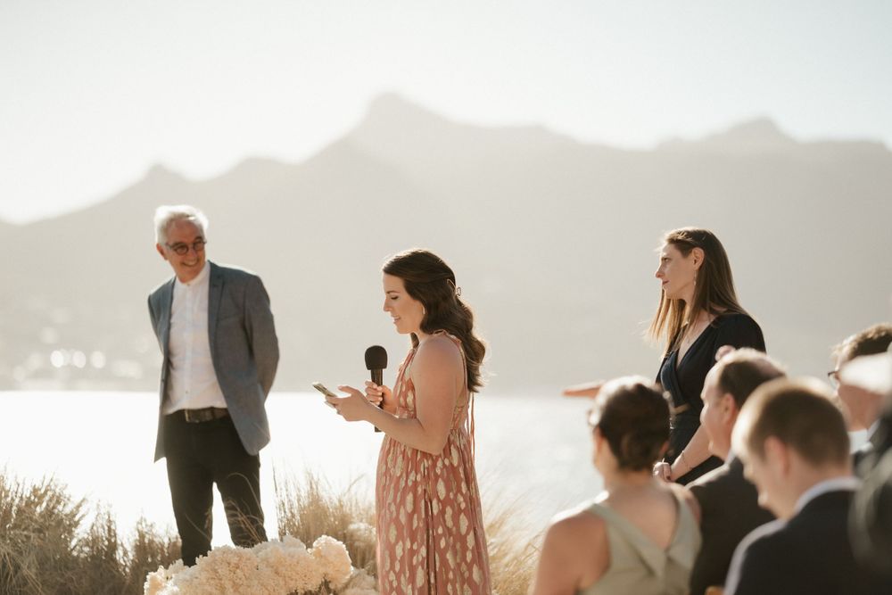 An outdoor ceremony takes place against a backdrop of misty mountains and water.