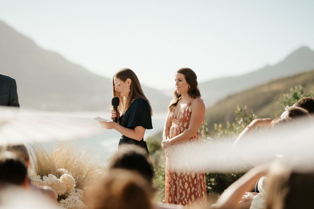 Guests watching outdoor ceremony with scenic mountain and ocean backdrop.