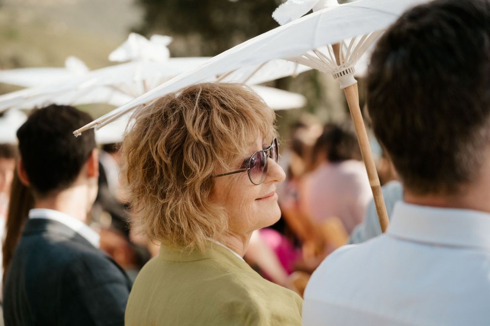 Wedding guests gather under white parasols during an outdoor celebration.