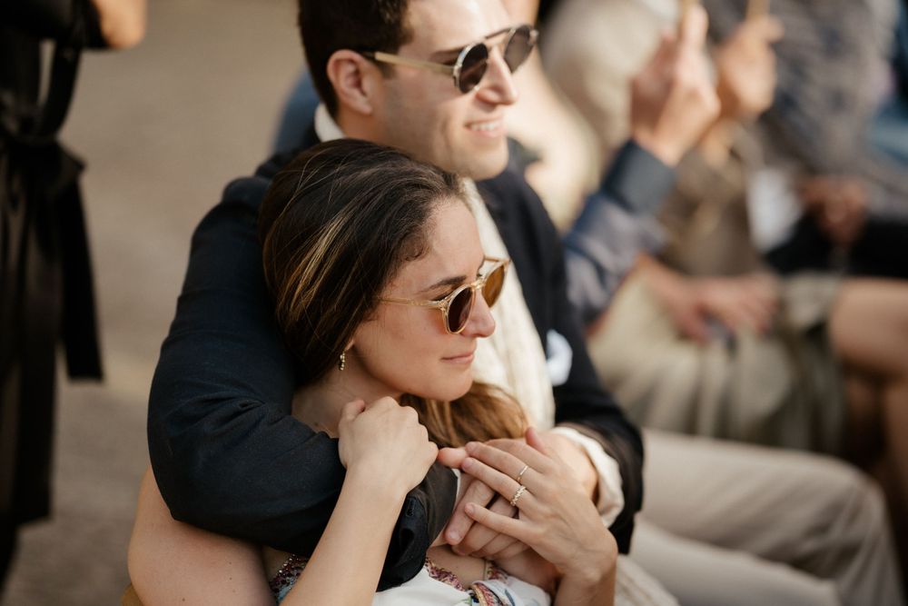 Couple in sunglasses sharing an intimate moment at an outdoor event.