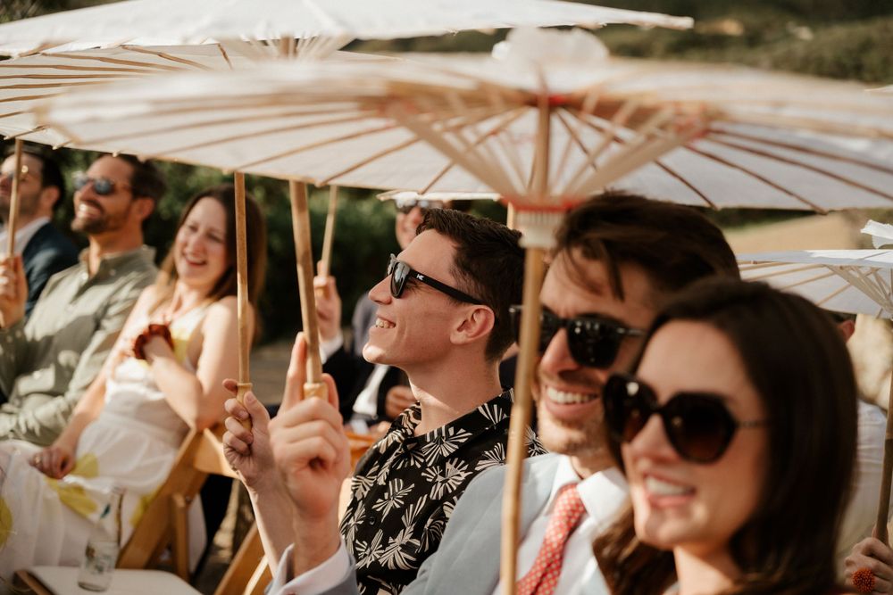 Stylish guests hold decorative parasols while enjoying an outdoor celebration.