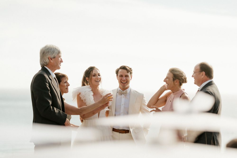 Wedding party gathered for candid moment against misty coastal backdrop.