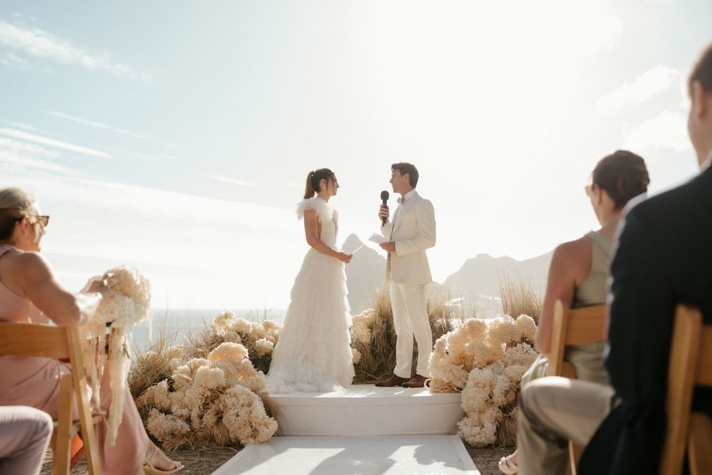 Outdoor wedding ceremony overlooking ocean with white floral decorations.